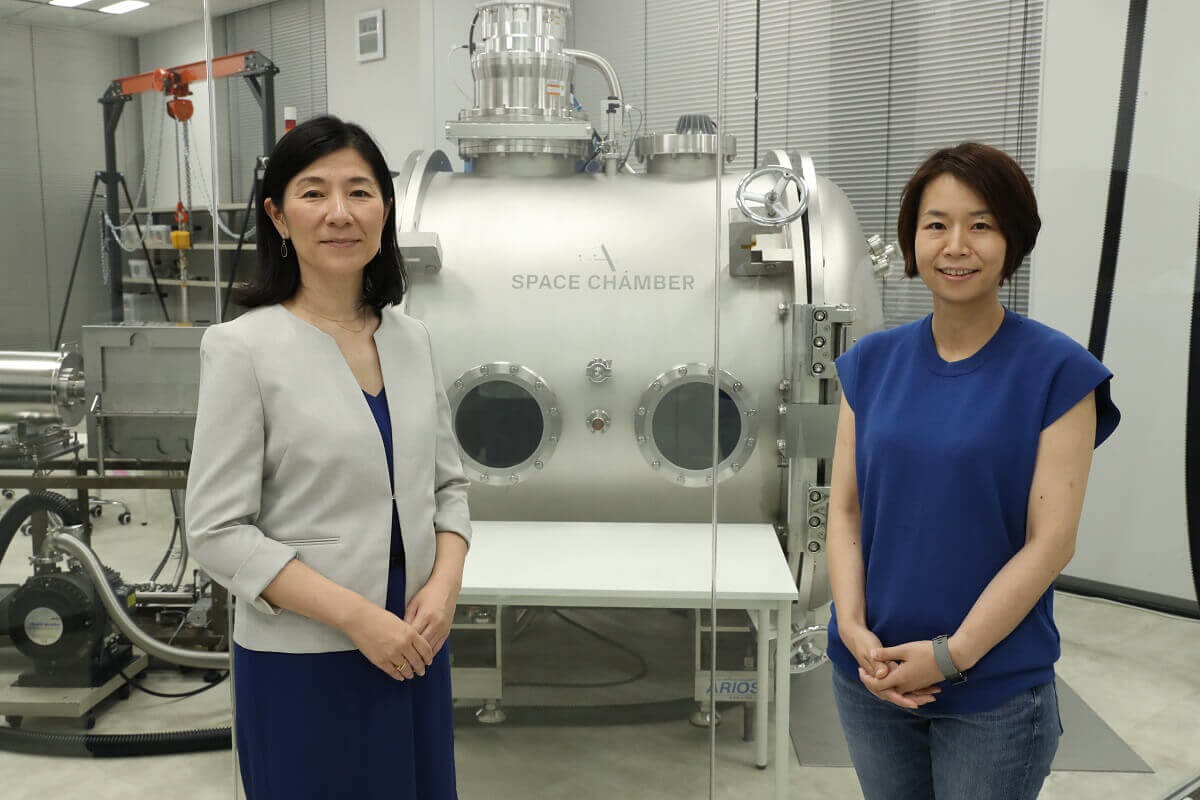 Ms. Lena Okajima (right) of ALE and Ms. Norinaga at MTC in front of the vacuum chamber