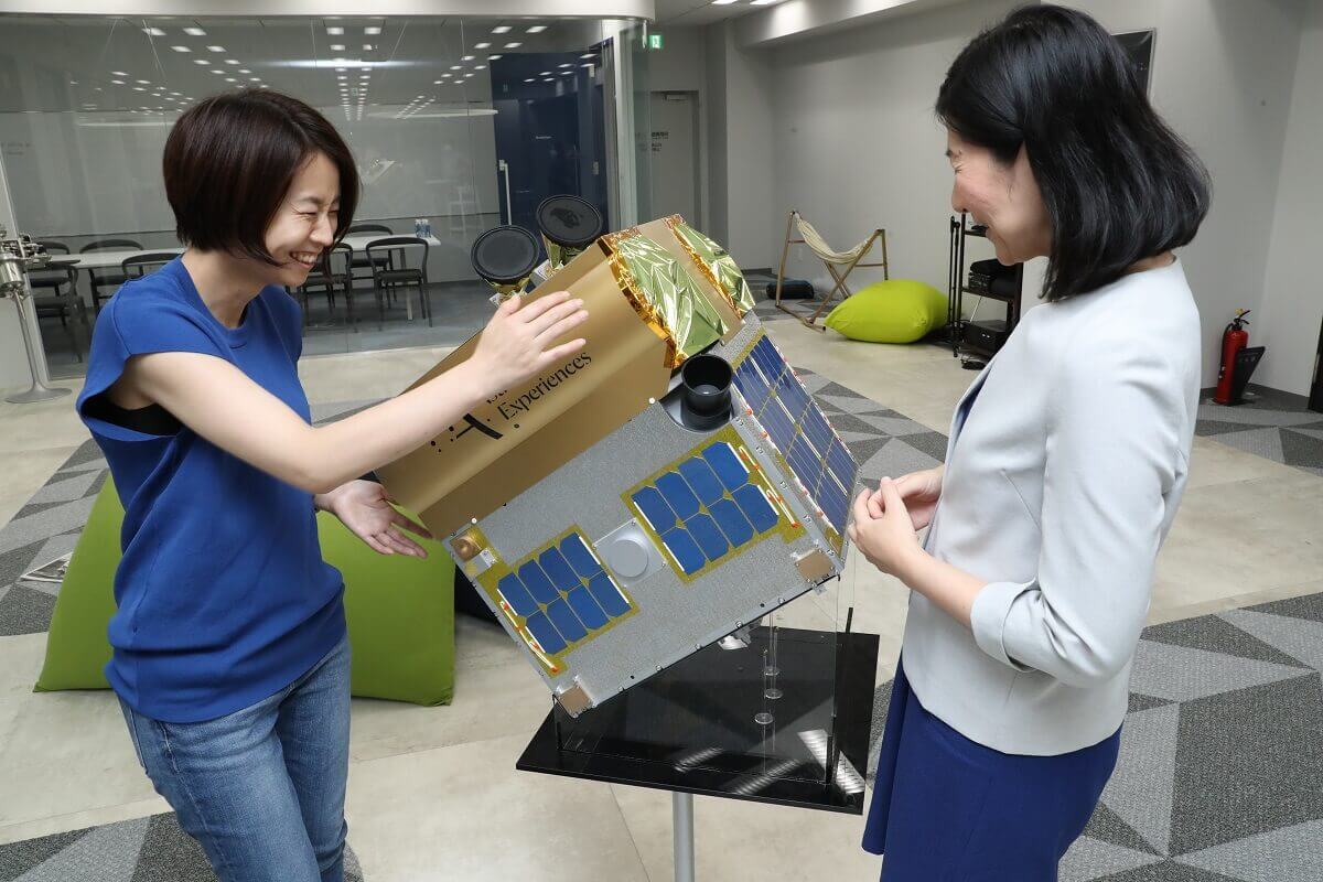 Ms. Lena Okajima of ALE (left) and Ms. Norinaga holding a model of a satellite